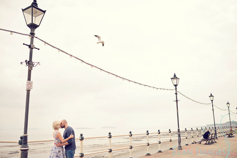 A lone seagul flying over the couple during their engagement photo shoot in Cardiff