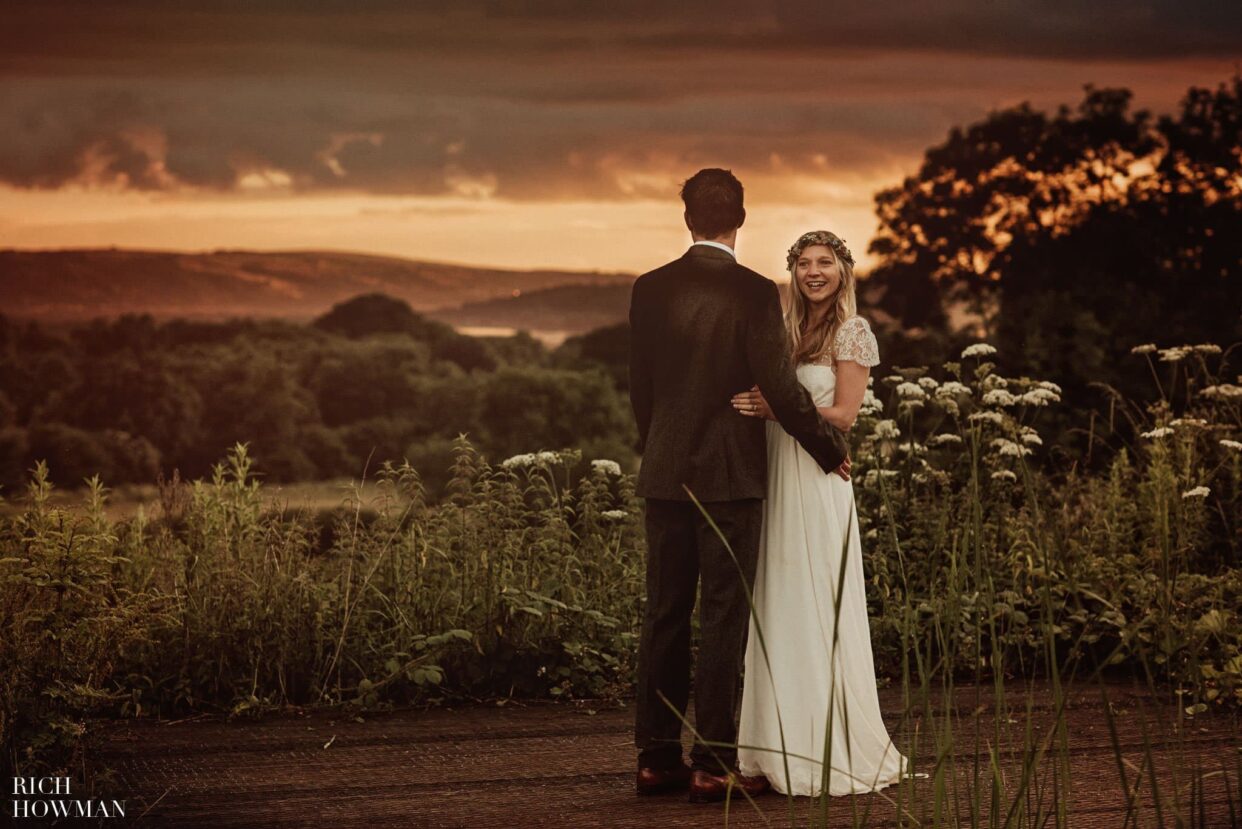 bride smiles with groom as they overlook sunset in the valley after their folly farm centre wedding
