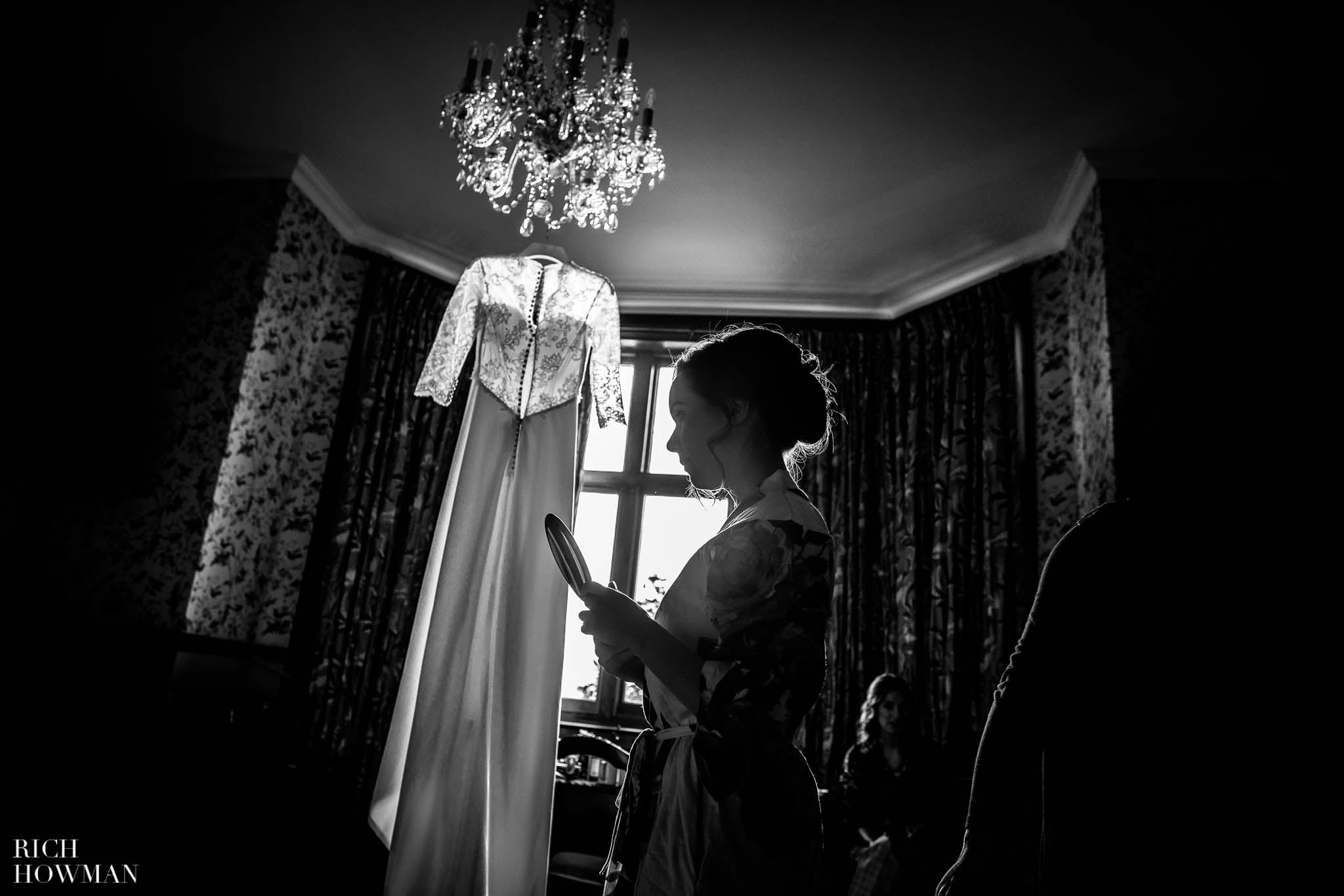 wedding dress hanging in window light, black and white photo captured byHuntsham Court wedding photographer Rich Howman