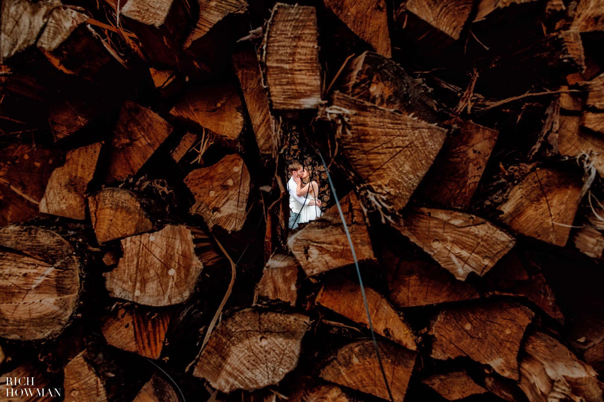 bride and groom portrait between wood pile, captured by Rich Howman, Aldwick Court Wedding Photographers