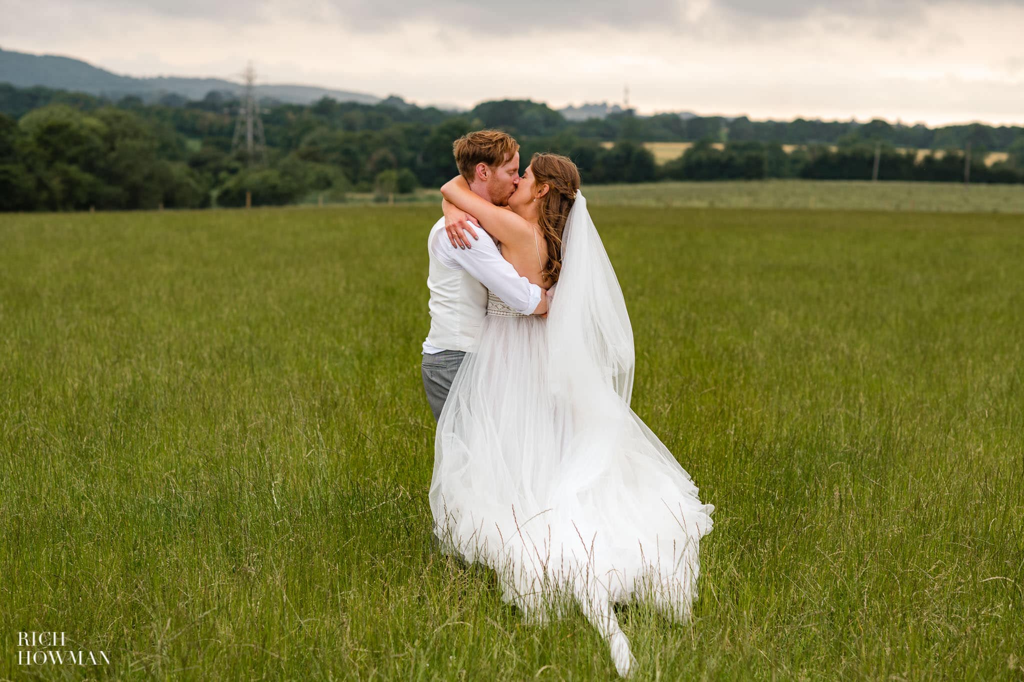 bride and groom kiss in a field captured by Aldwick court wedding photographer, Rich Howman