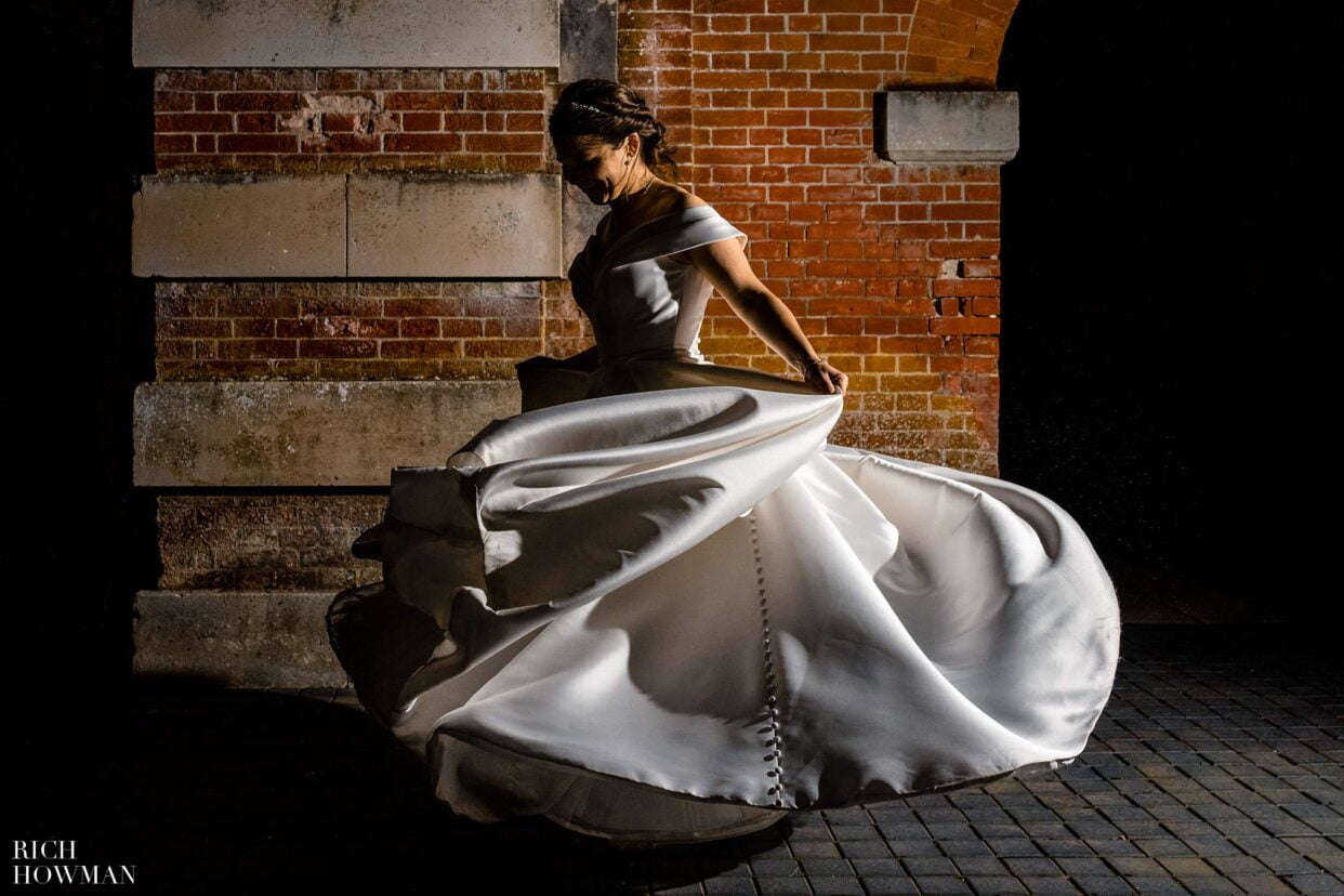 bride swirling beautiful wedding gown in creative night time portrait by dorset wedding photographer rich howman