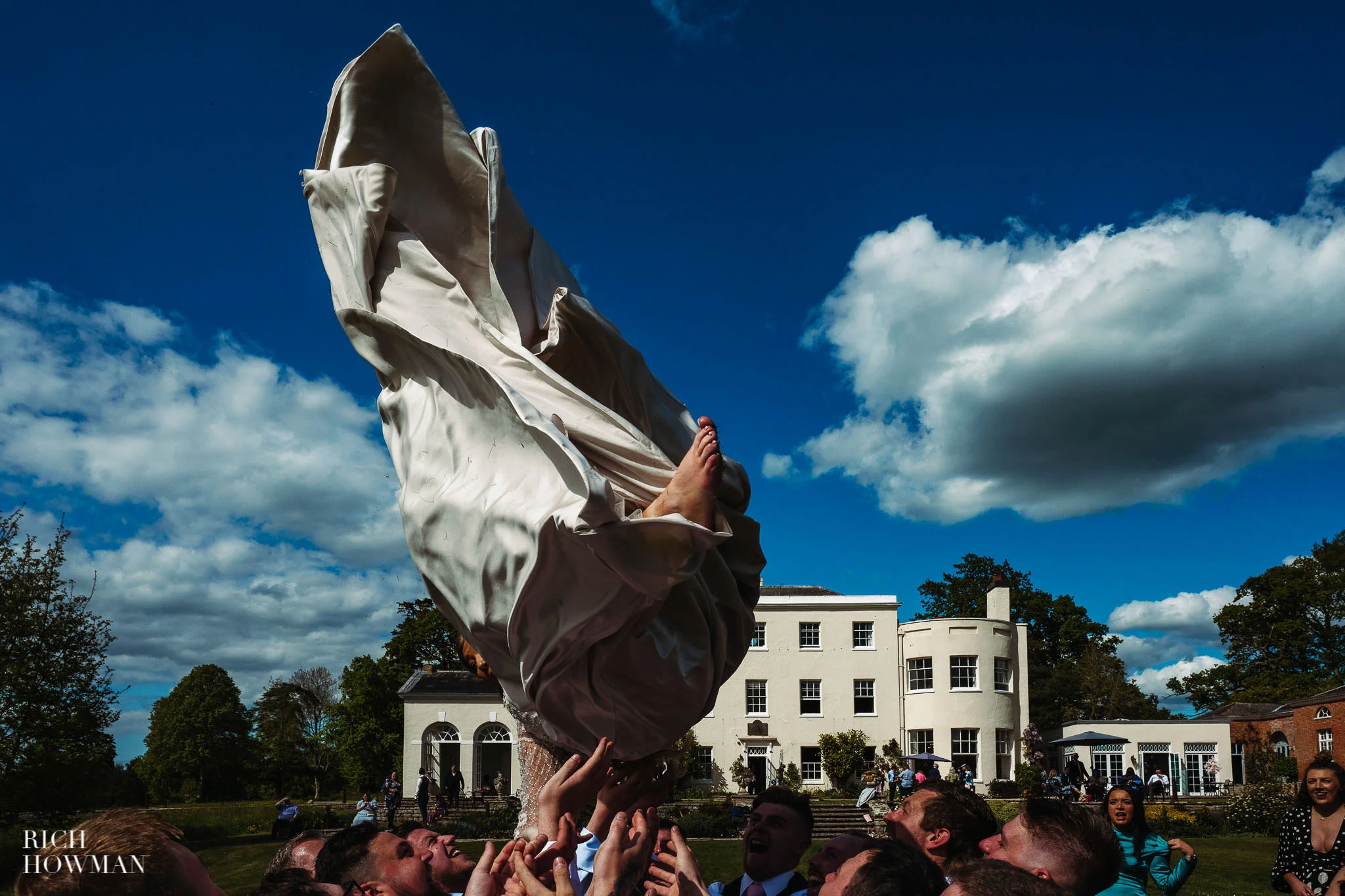 bride thrown in the air by guests captured by rockbeare manor wedding photographer Rich Howman