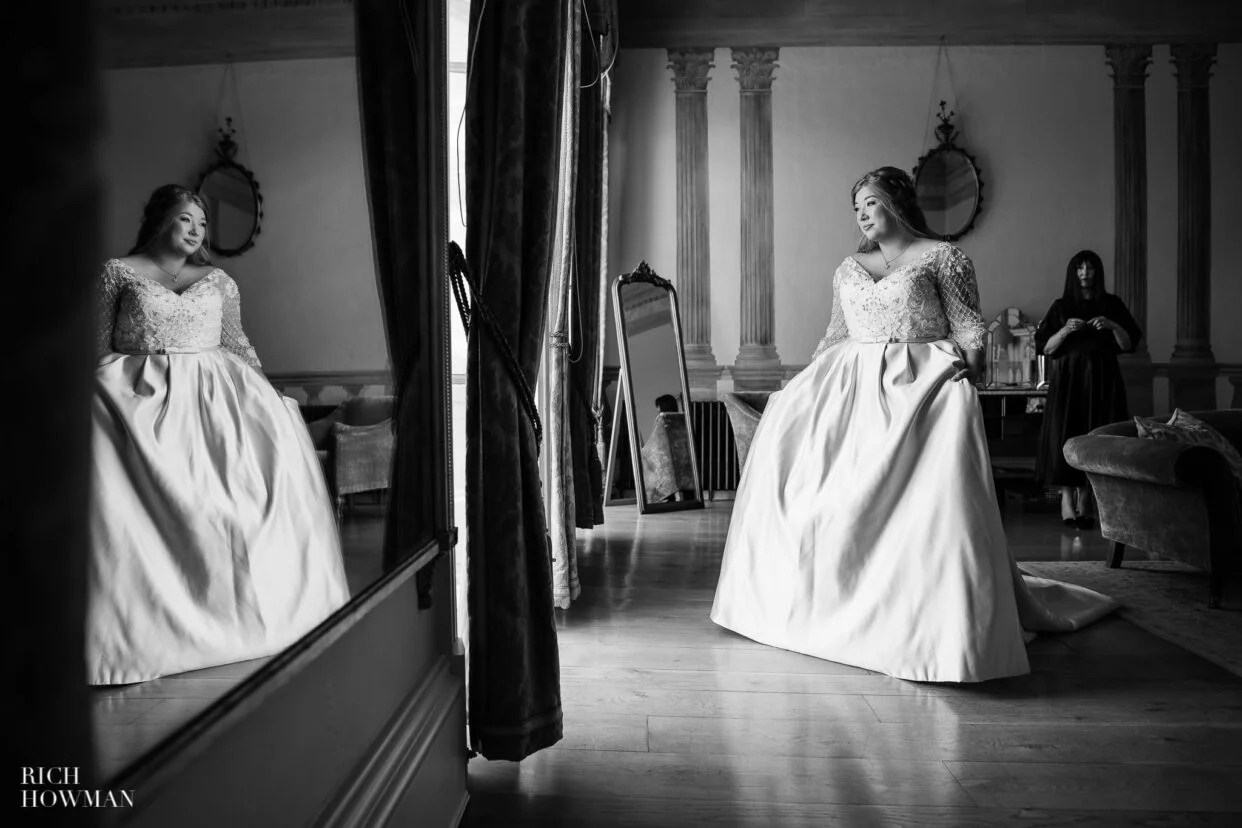 bride in front of window with mirror reflection captured by rockbeare manor wedding photographer, rich howman