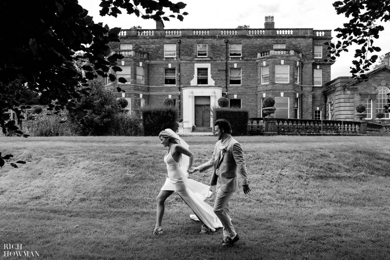 bride and groom walking hand in hand captured by bredenbury court barns wedding photographer, rich howman