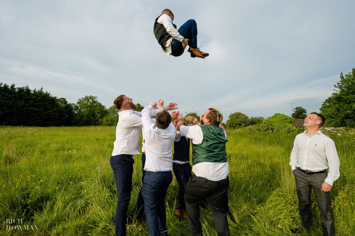 groomsman getting thrown in the air by bridal party captured by moonraker hotel wedding photographer rich howman