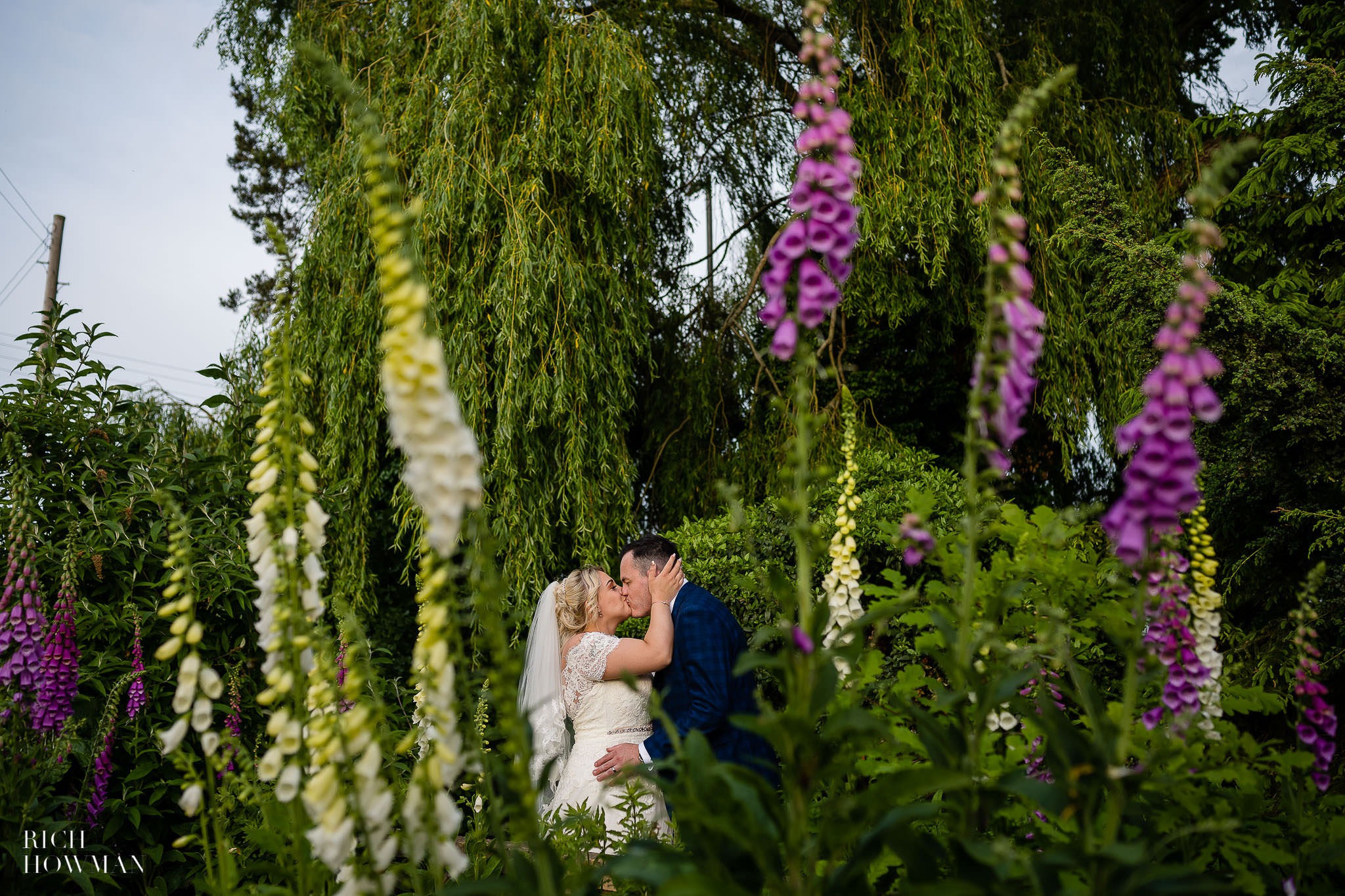 bride and groom kissing framed with flowers by moonraker hotel wedding photographer, rich howman