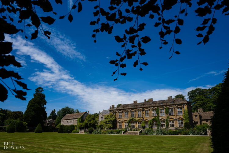front of the main house under a bright blue sky,captured by brympton house wedding photographer rich howman