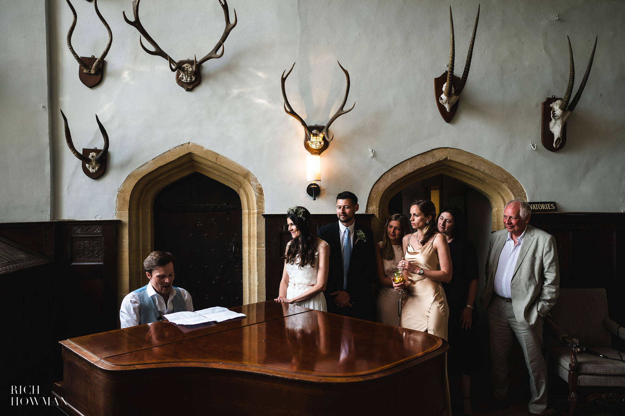 groom plays song for his bride on grand piano, captured by brympton house wedding photographer, rich howman