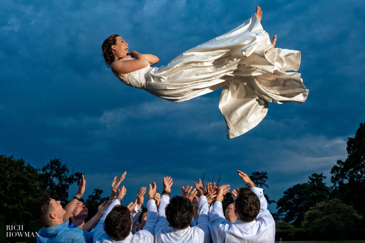 bride being thrown in the air, captured by Hengrave Hall wedding photographer, rich howman