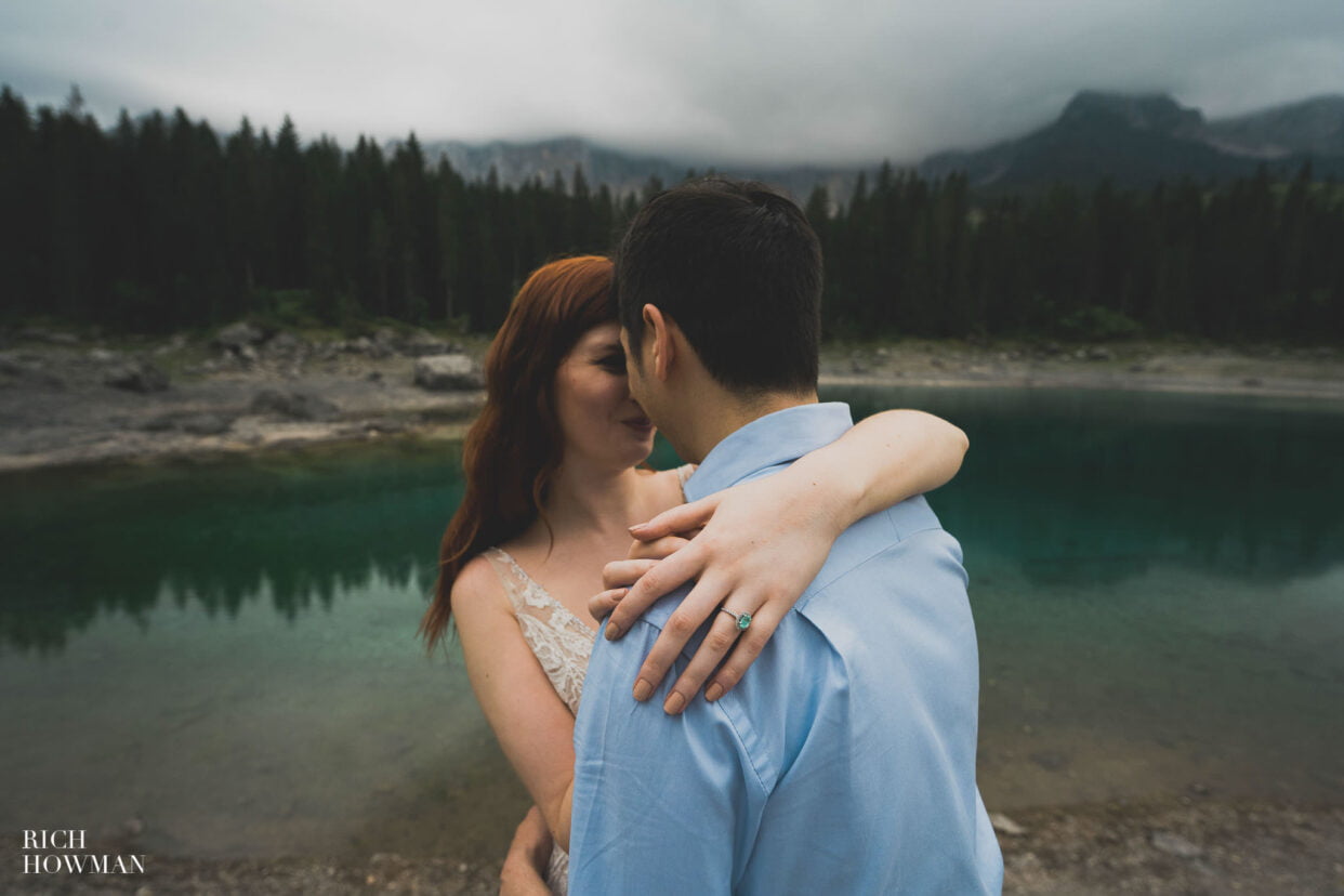 bride and groom embrace next to azure lake, captured by dolomites wedding photographer, Rich Howman