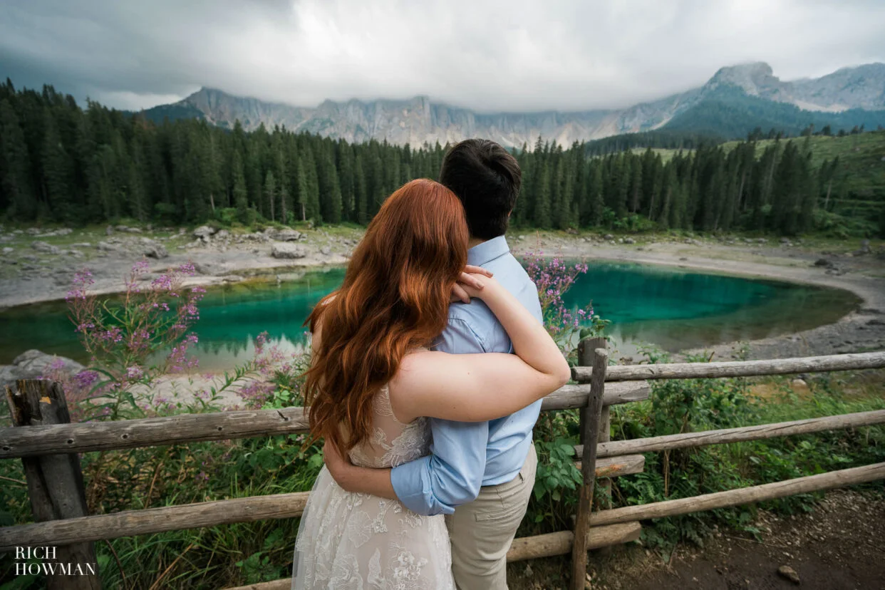 couple overlook a lake and forest, captured by dolomites wedding photographer, Rich Howman