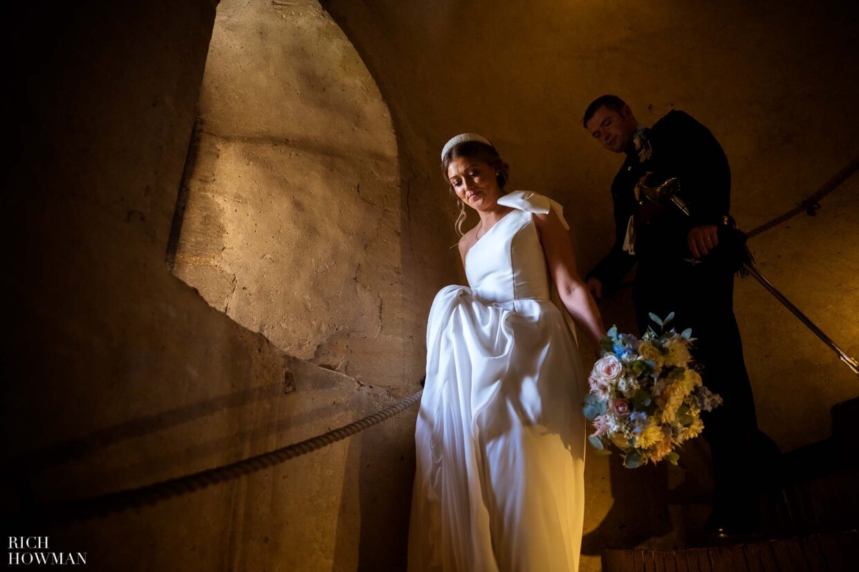 bride and groom descending castle stairs, captured by hedingham castle wedding photographer, rich howman