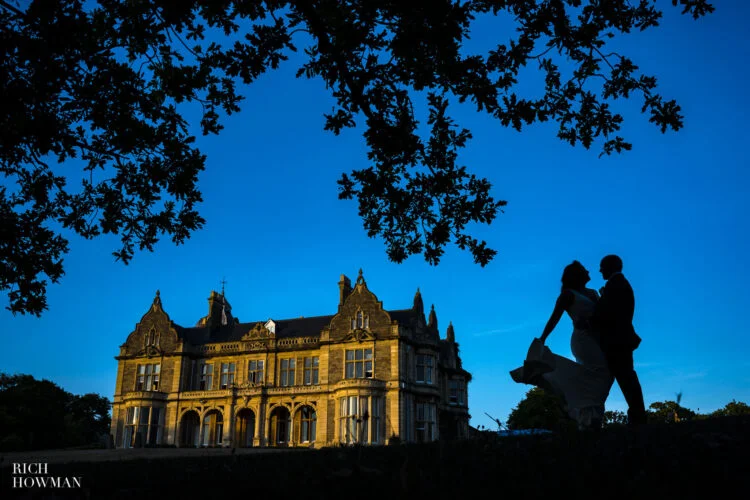 bride and groom silhouette in front of main house, captured by Clevedon Hall wedding photographer, Rich Howman