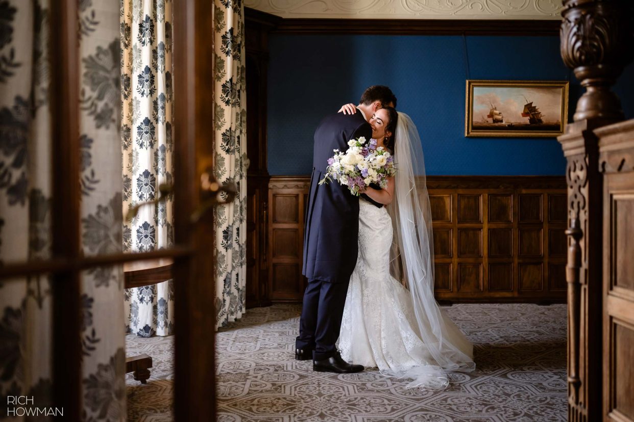 Bride and groom embrace in an oak panelled room on their wedding day, captured by Somerset Wedding Photographer, Rich Howman
