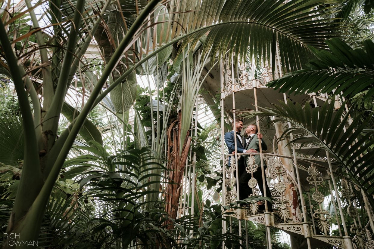 Grooms kiss on spiral staircase in the palm house captured by Cambridge Cottage wedding photographer, Rich Howman