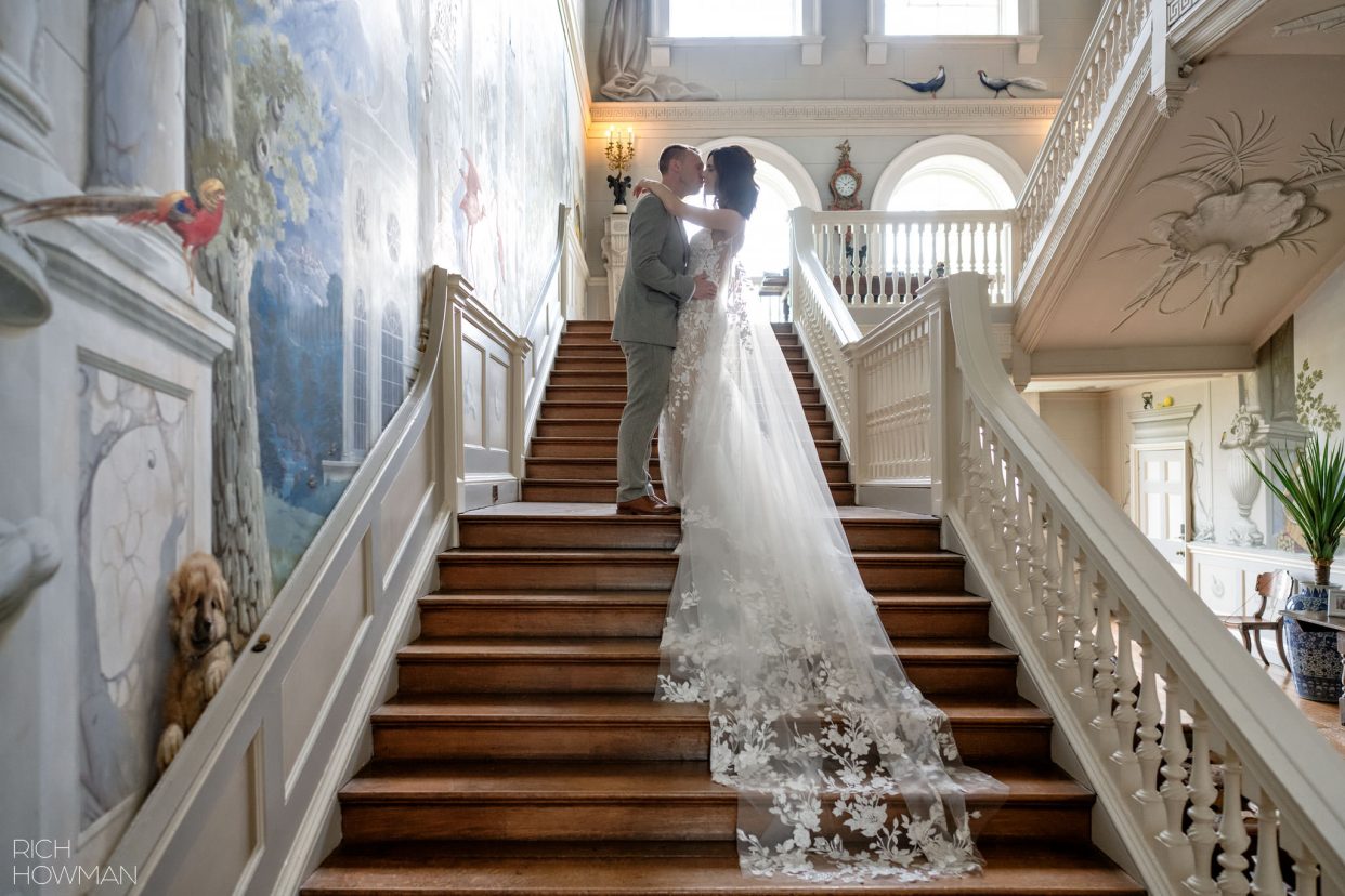 portrait of bride and groom on the staircase, with lace dress train details, captured by Ragley Hall wedding photographer, Rich Howman