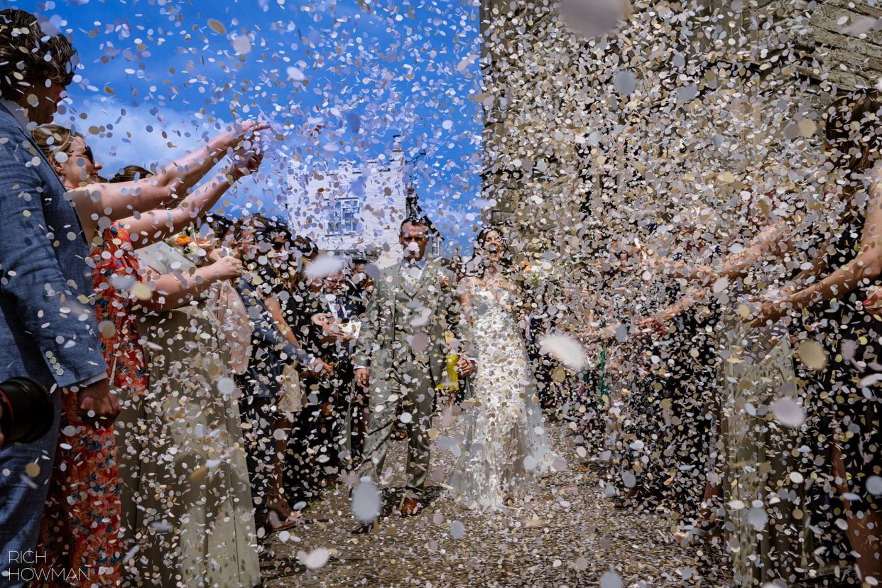 bride and groom showered in confetti captured by Ragley Hall wedding photographer, Rich Howman