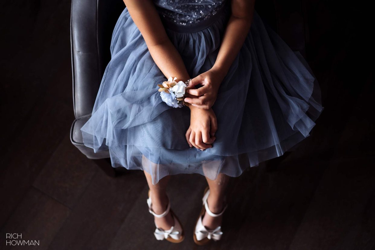 rearranging her corsage wearing a blue dress and white shoes, captured by hotel du vin Bristol wedding photographer, Rich Howman